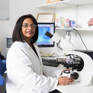 Female scientist sitting in lab with microscope