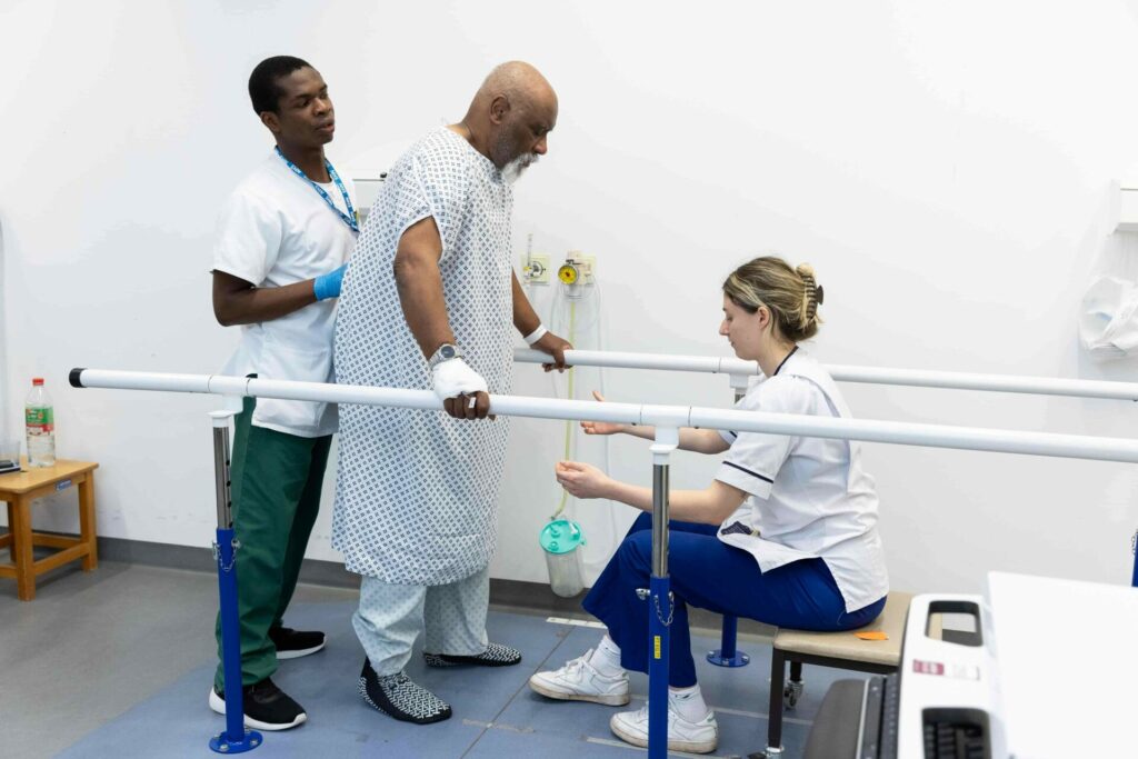 Male patient doing walking rehab with a male and female physios.